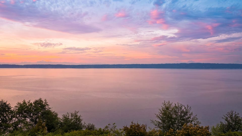 Watch the sky turn shades of pink and lavender over the Sound, with distant mountain silhouettes along the horizon.
