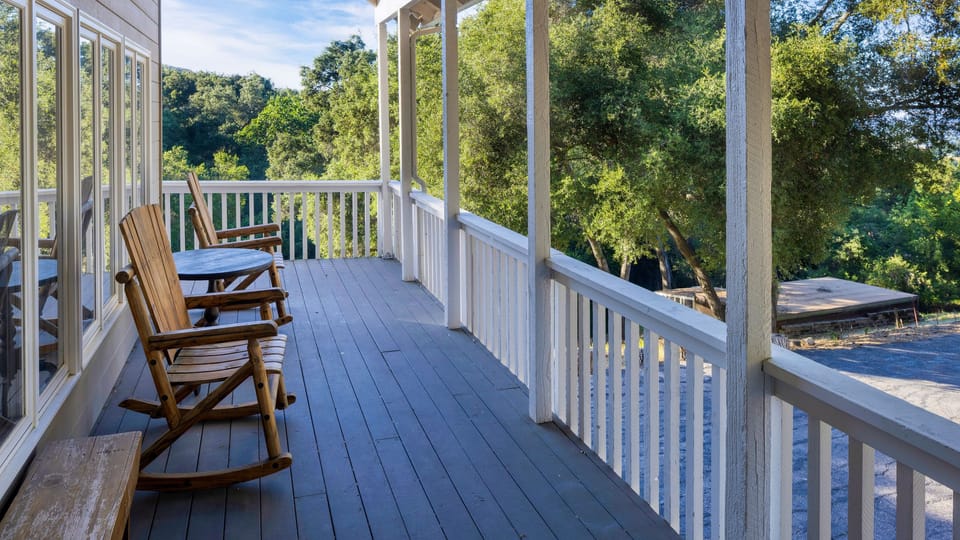 Covered porch with rocking chairs overlooking peaceful wooded views.