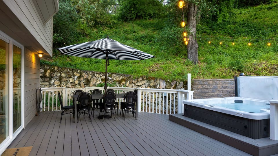 Private deck with hot tub, outdoor dining, and ambient string lighting.