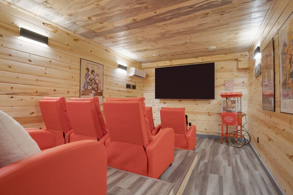 Private theater room with plush recliners, big screen, and classic popcorn machine for movie nights.