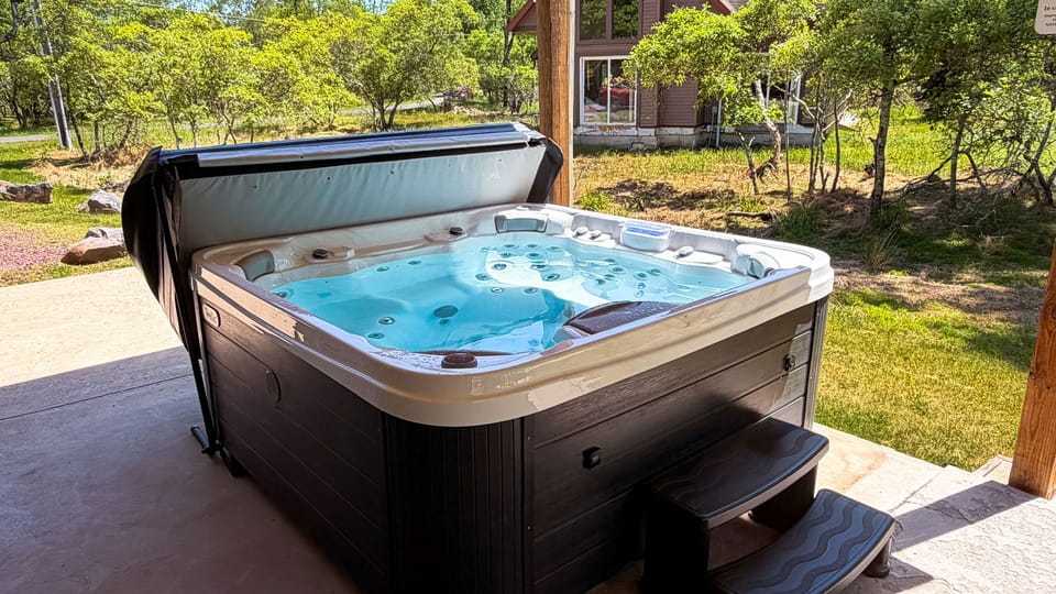 Covered hot tub with peaceful wooded views for a relaxing soak after a day outdoors.