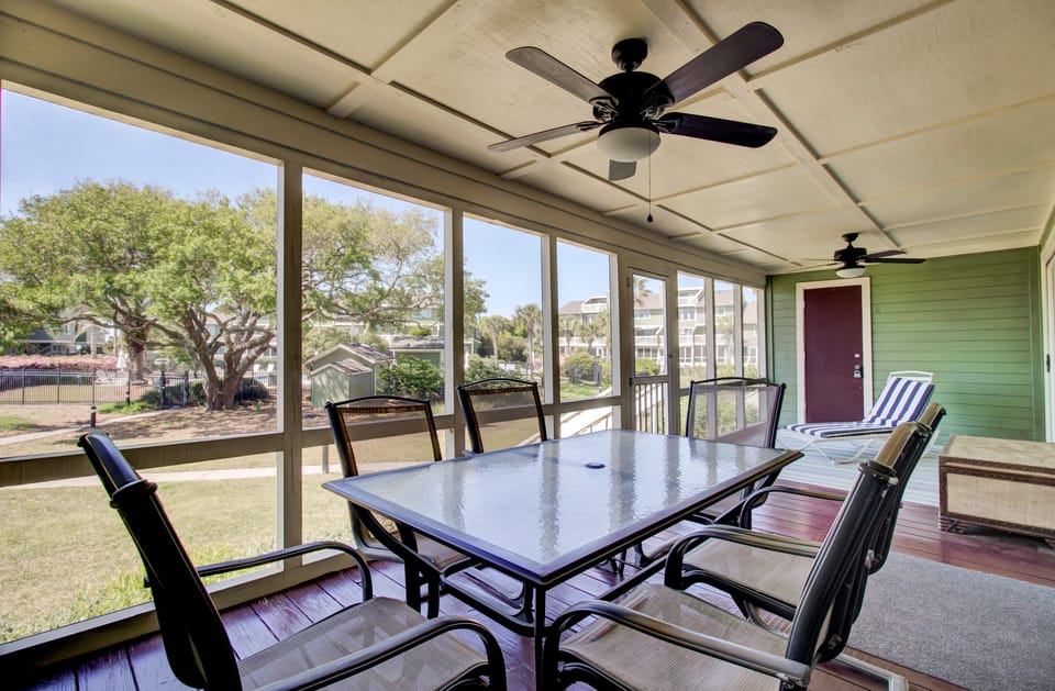 Enclosed porch features a dining table and loungers.