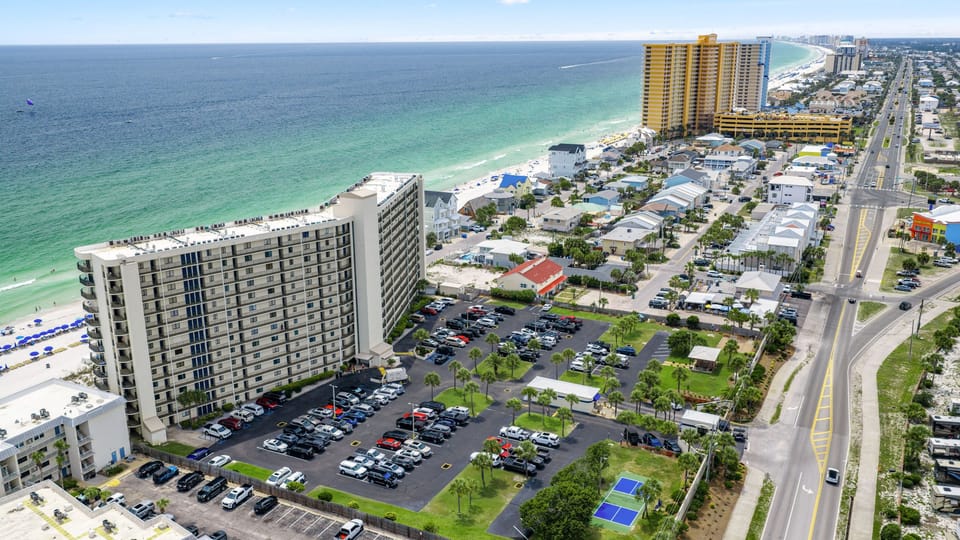 Aerial view of the beachfront area with turquoise Gulf waters, nearby resorts, and coastal attractions close by.
