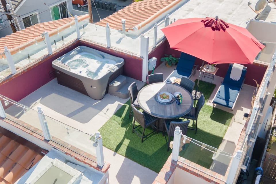 Rooftop patio with a hot tub, dining area, and sun loungers.