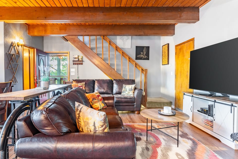 Warm wood beams, rich leather seating, and a cozy open layout create the perfect mountain gathering space for movie nights and relaxed evenings in.