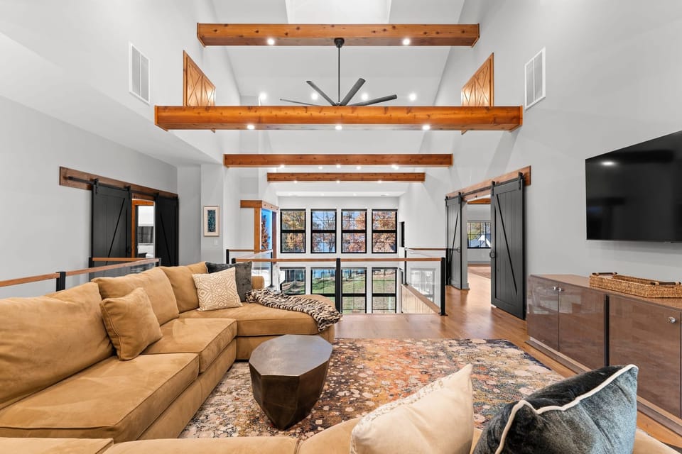 Upper Level family room with large sectional and TV- with barn doors to 2 suites of 2 bedrooms each and bathroom.