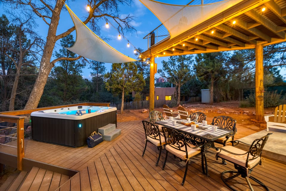 Entertainer's paradise with an outdoor dining table, hot tub, and evening lighting.