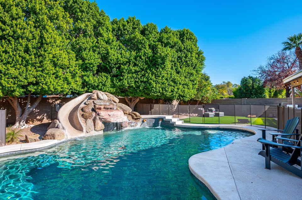 Backyard oasis features a pool with a waterslide.