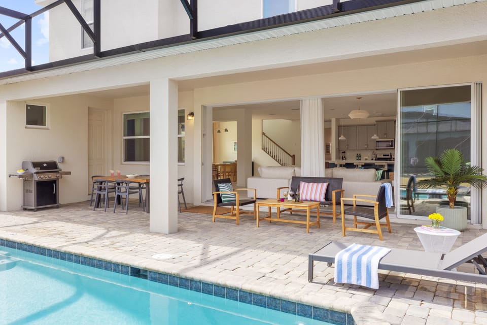 The living room features floor-to-ceiling windows, a TV, and a large sectional sofa.