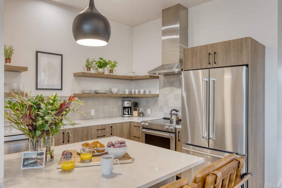 Modern kitchen with island seating and stainless appliances.