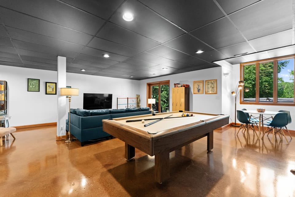 Game room with pool table, working space table, TV, and books, perfect for entertainment.
