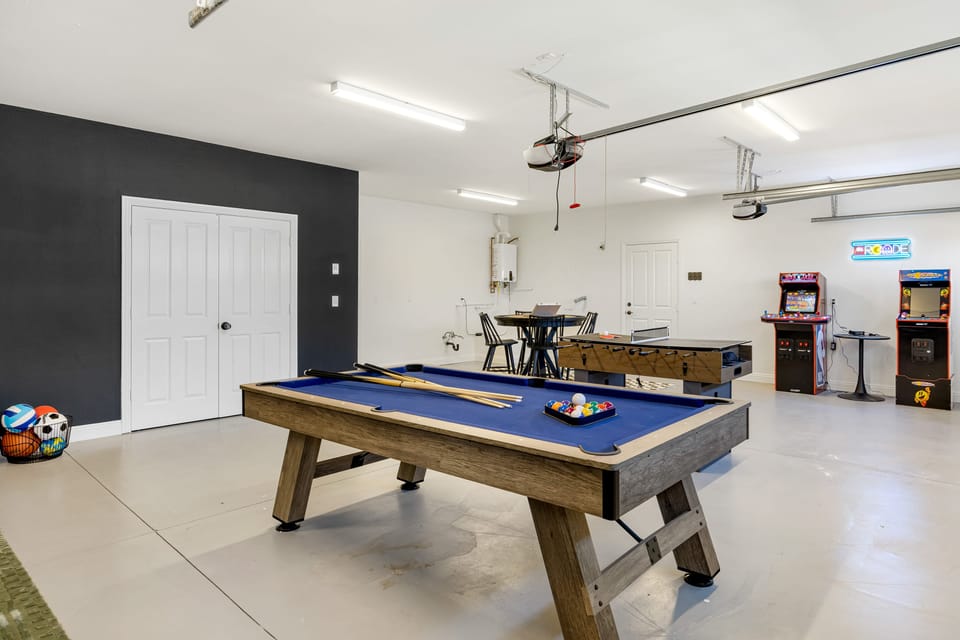 The garage game room offers a pool table, foosball table/ping pong, an arcade, and a TV.
