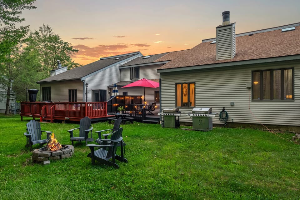 Spacious, lush backyard with a firepit, two grills, and plenty of outdoor seating for relaxing or dining al fresco.