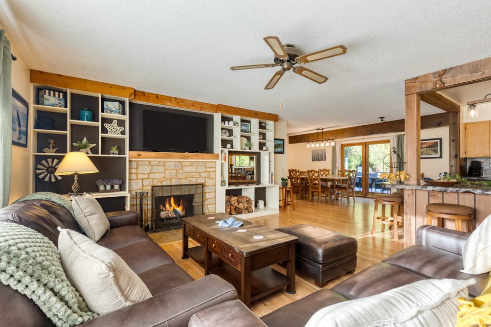 Relax in the cozy living room with a fireplace, flat-screen TV, and custom shelving.