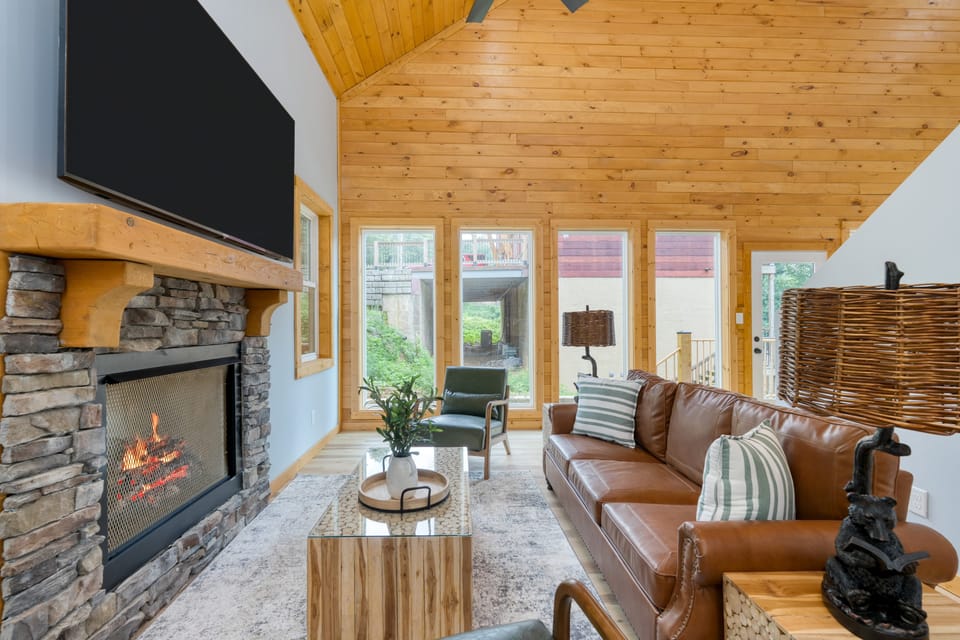 Bright and airy living room with a leather couch, fireplace and TV.