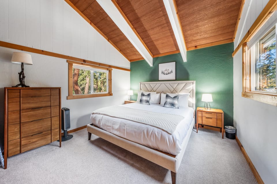 Serene bedroom under exposed beams, with soothing green accent wall.