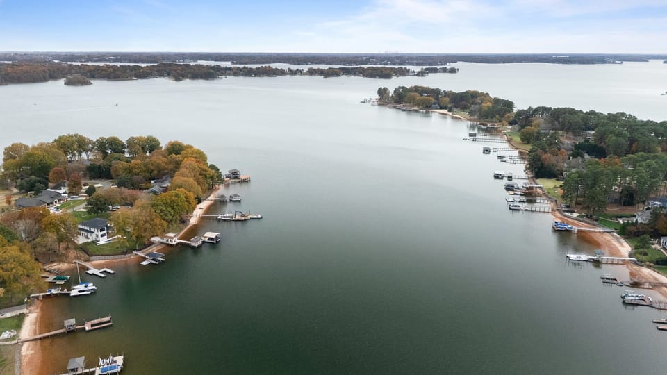 Aerial view of the peaceful lakeside neighborhood with private docks and calm shoreline waters.