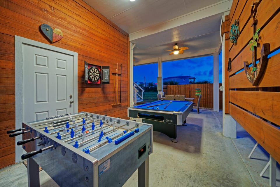 Game/covered patio area with pool table, foosball, bar table, dining table, and BBQ grill.