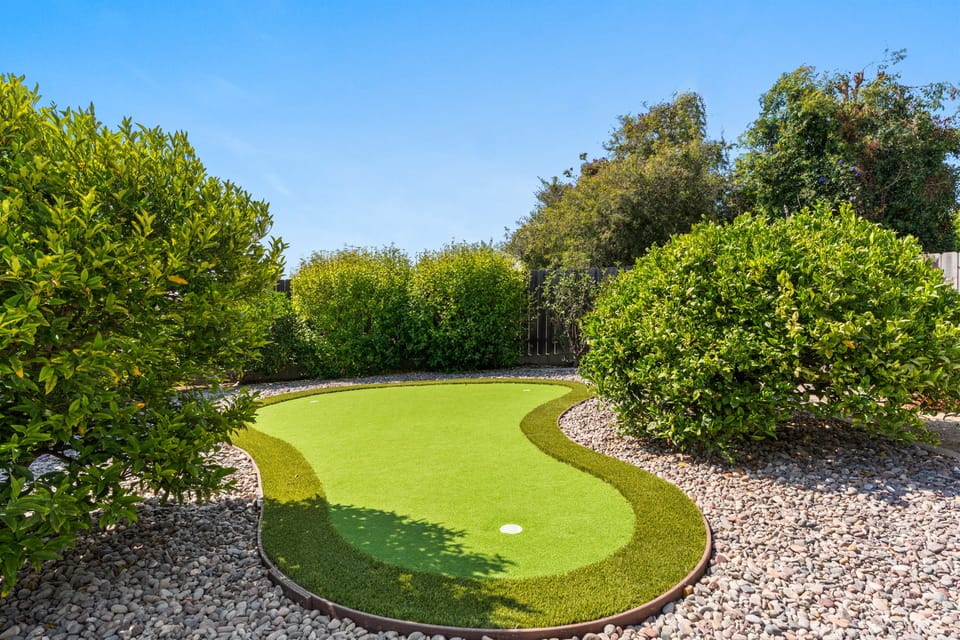 Backyard putting green with lush landscaping.