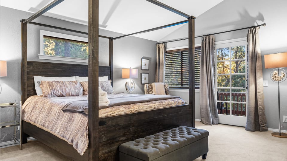 Primary bedroom with a canopy bed and balcony access.