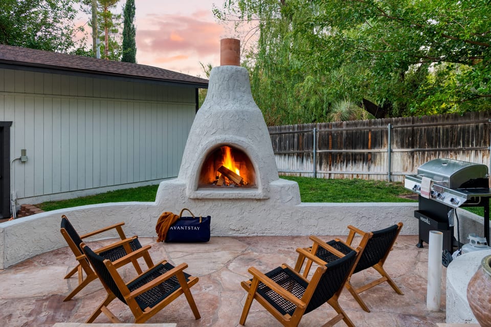An enchanting backyard retreat with a unique chiminea fireplace, comfortable seating, and a grill for outdoor dining.