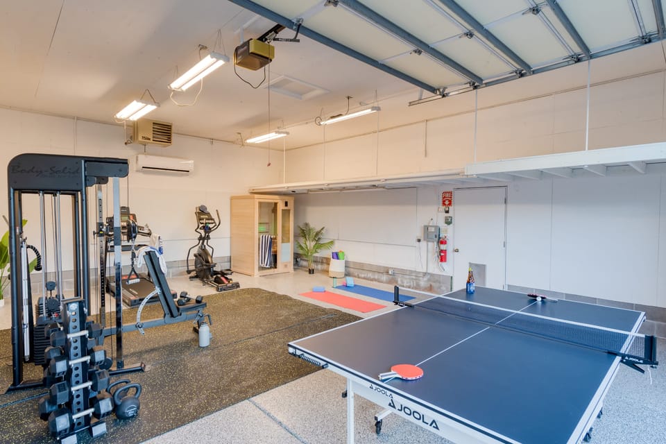 Dedicated fitness and recreation area featuring a multi-station gym, a serene sauna, and a ping pong setup for friendly competition.