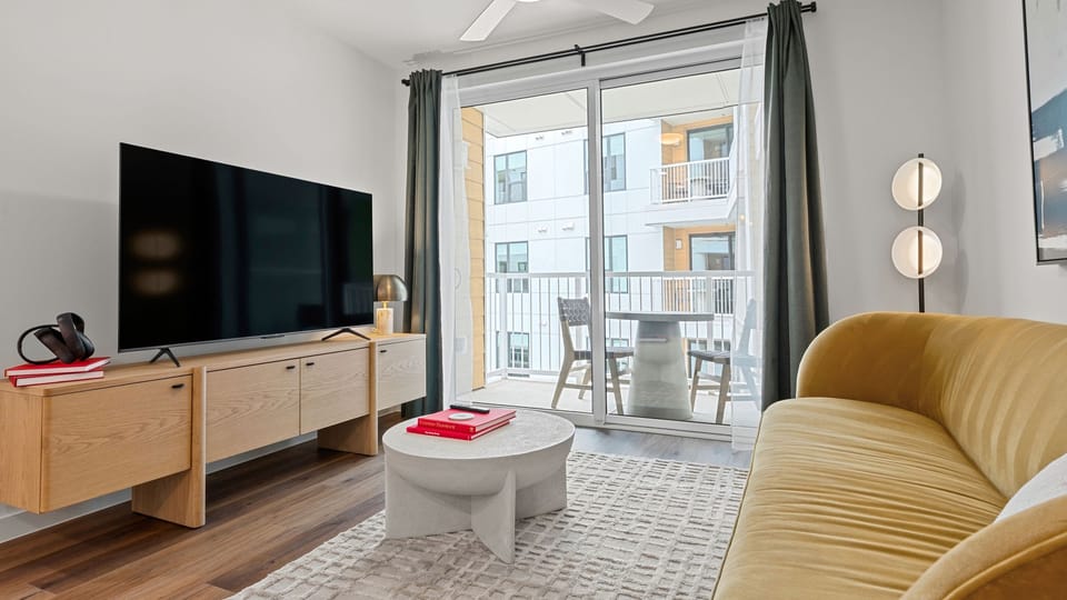 Relax in the stylish living area featuring a pull-out sofa, smart TV, and private balcony access for seamless indoor-outdoor living.