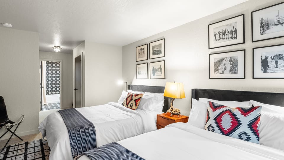 The bedroom features 2 queen beds, TV, deck access and an ensuite bathroom.