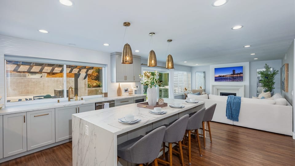 Open-concept kitchen with barstool seating, waterfall counter island, and pendant lights.