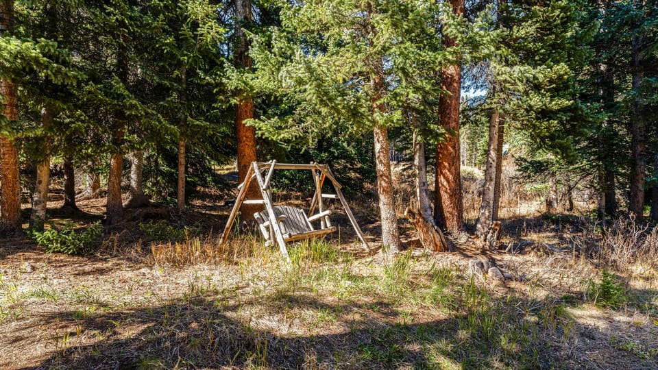 Backyard with forest views and a wooden swing chair.