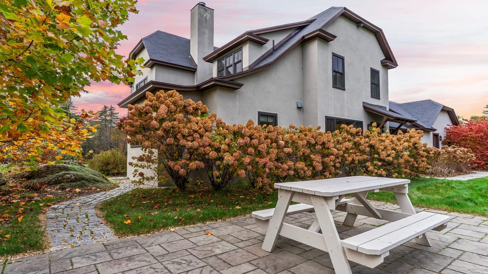 Exterior of home with stone patio and picnic table.