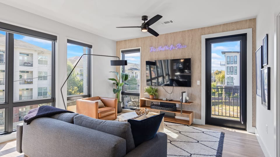 Bright living room with TV and large sunlit windows