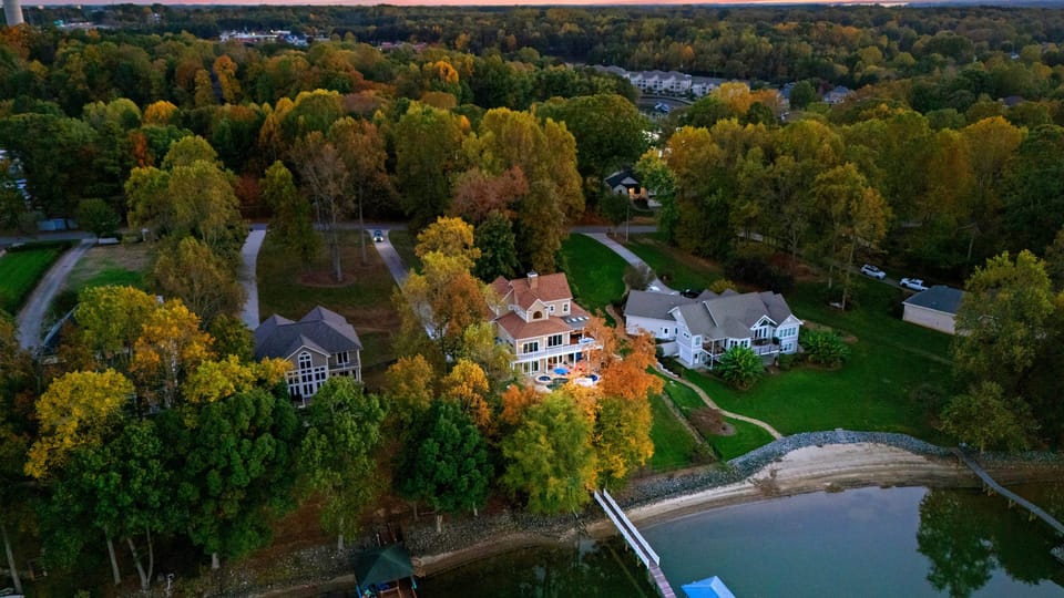 Aerial view of waterfront homes surrounded by dense autumn trees.