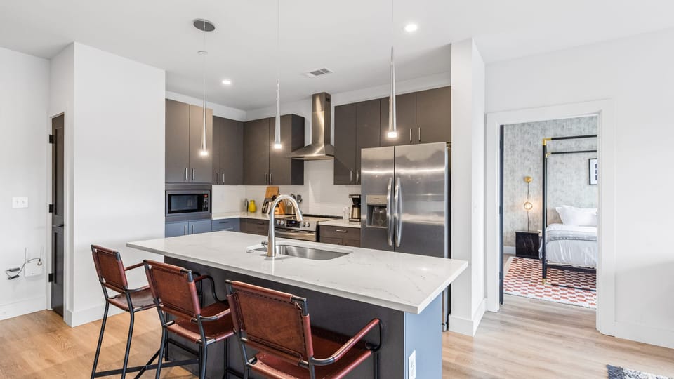 Modern kitchen with island seating and stainless steel appliances.