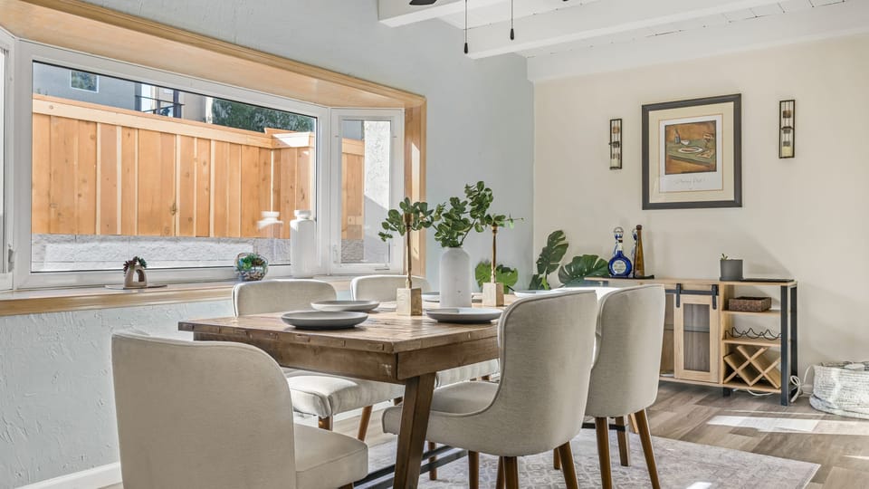 Bright, welcoming dining area featuring a rustic wood table, modern seating, and abundant natural light.