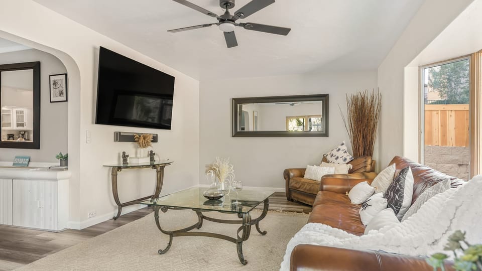 Secondary living space with a leather couch, TV, and outdoor views.