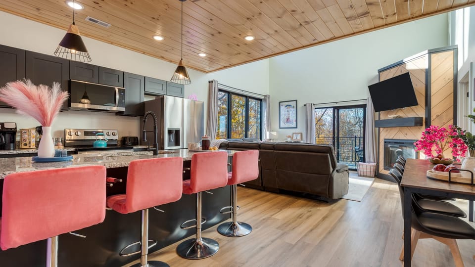 Bright, modern open-concept living with stylish pops of color and forest views.