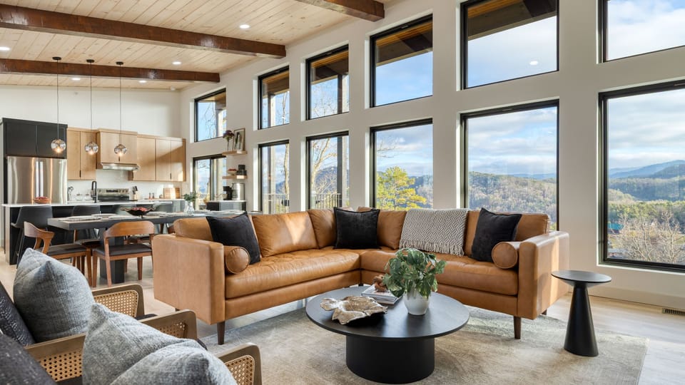 Bright open-concept living area with floor-to-ceiling windows framing panoramic Smoky Mountain views.