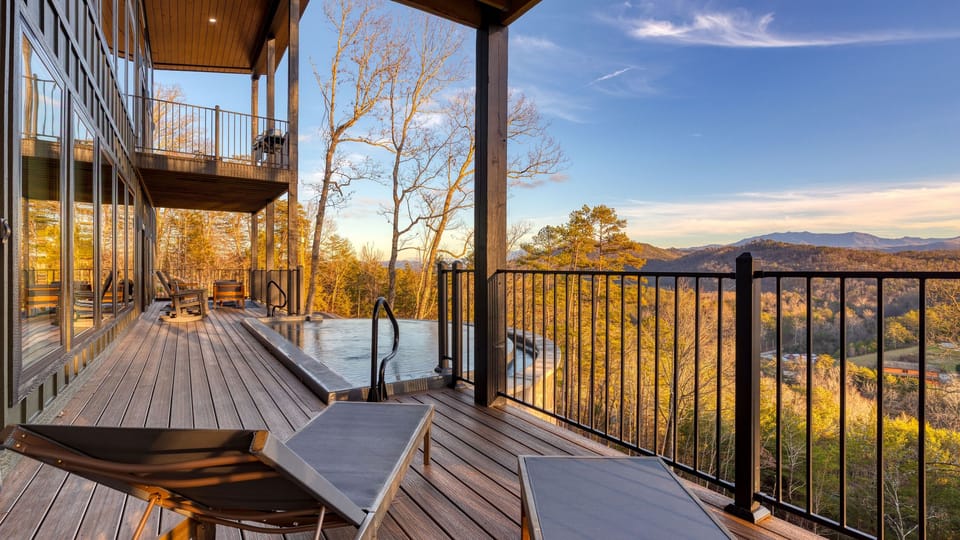 Terrace-level infinity pool and loungers overlooking sweeping Smoky Mountain vistas bathed in golden hour light.