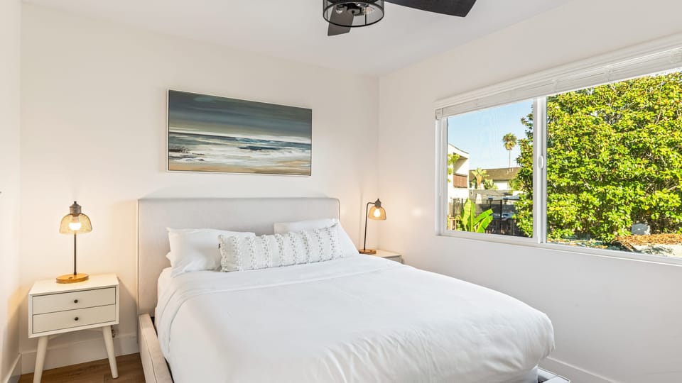 Bedroom 2 with white linens and wall art.