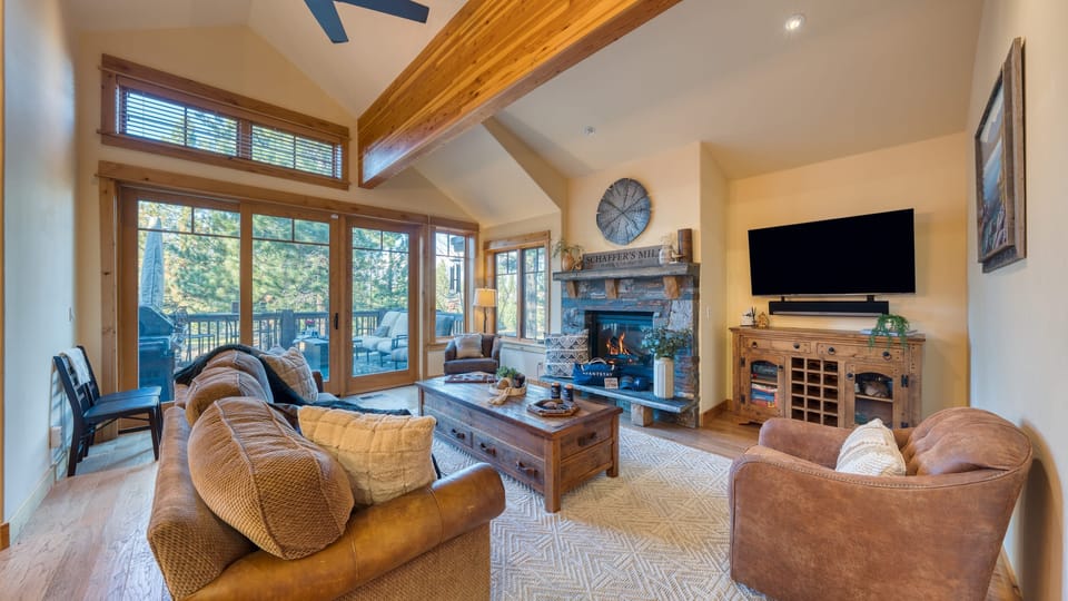 Gather fireside in the living room with stunning forest views through floor-to-ceiling windows.