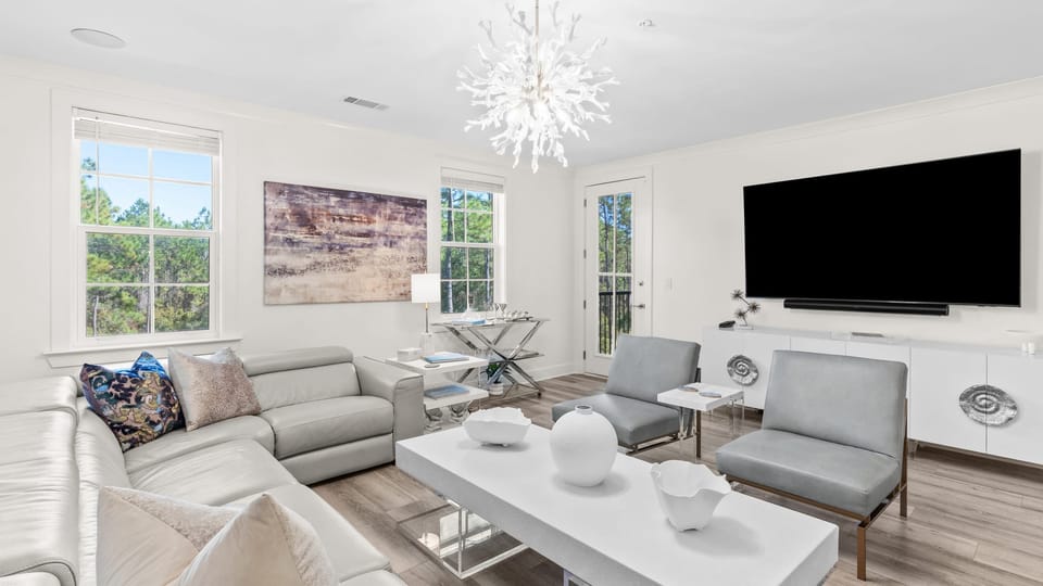 Bright, modern living room with plush seating and large windows overlooking the trees.