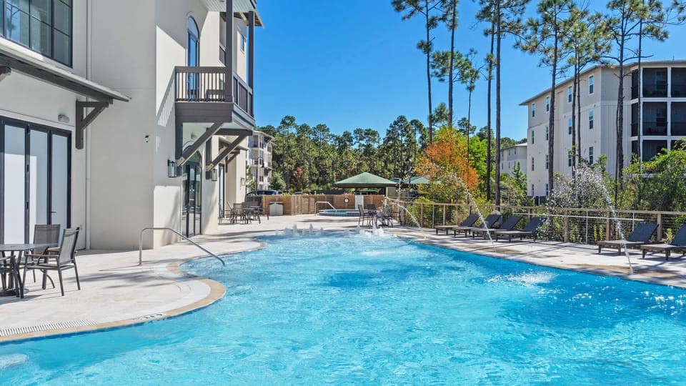 Relax by the sparkling community pool featuring fountains, sun loungers, and forest views.