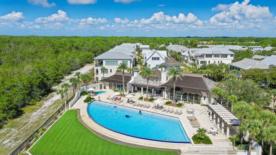 Community pool and clubhouse with loungers and lawn.