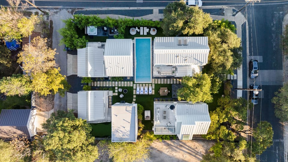 Golden-hour glow over a modern oasis with poolside lounges and cozy firepit seating.