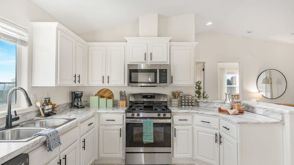 White kitchen with shaker cabinets, stainless steel appliances, and a gas stove.