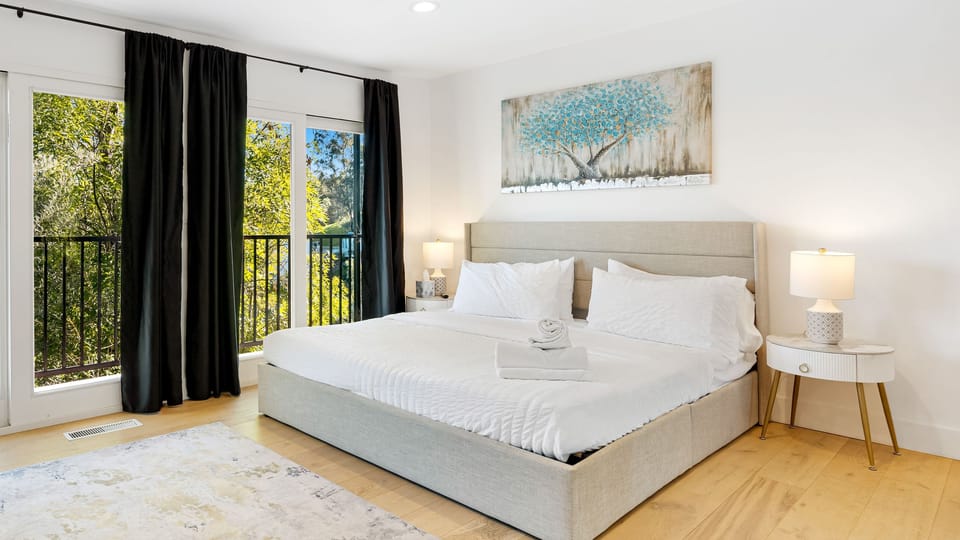 Primary bedroom featuring a king bed with large windows and direct outdoor access.