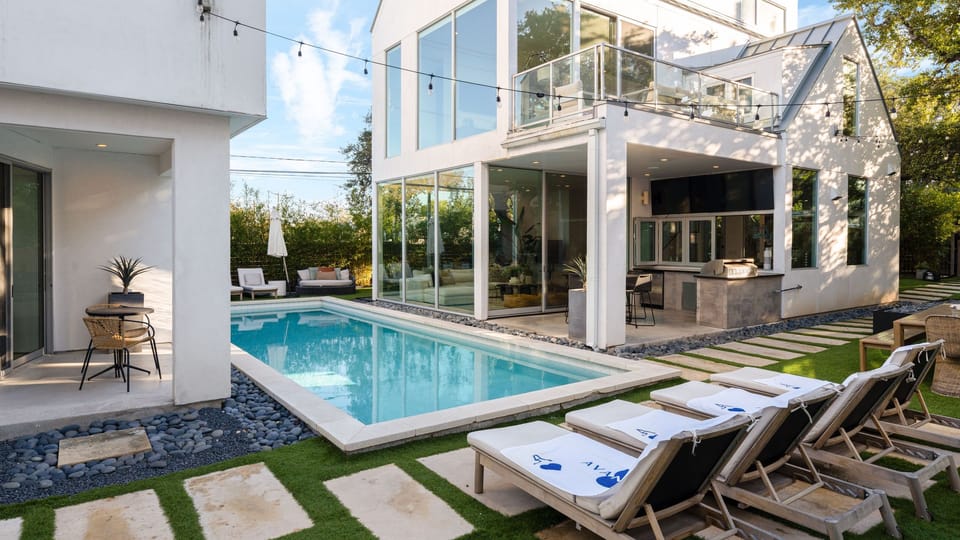 Shared outdoor retreat with a sleek pool, lounge chairs, and glowing string lights.