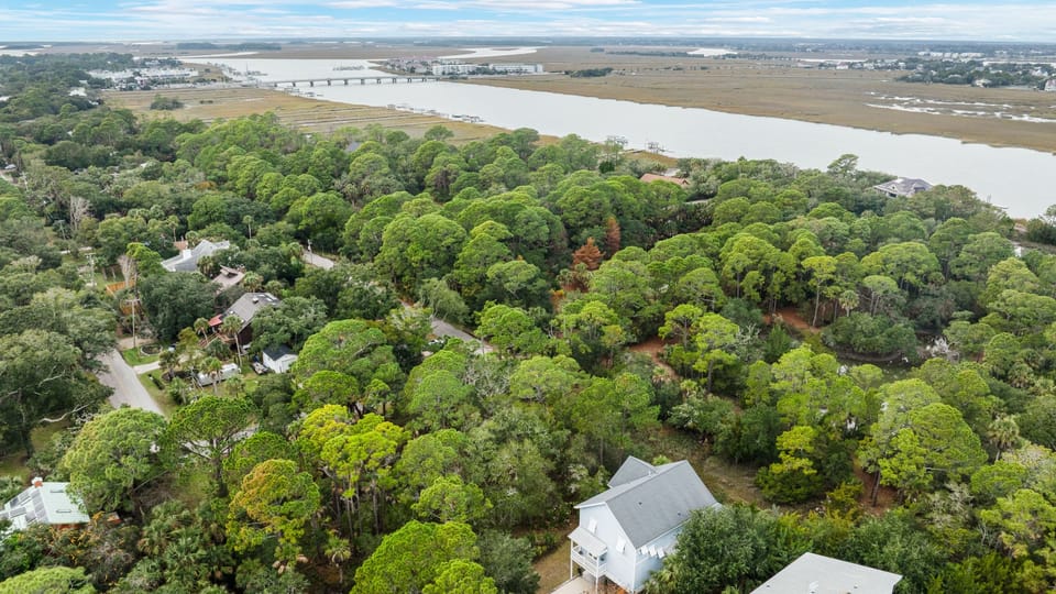 Wide aerial view showing the house and the surrounding green landscape.