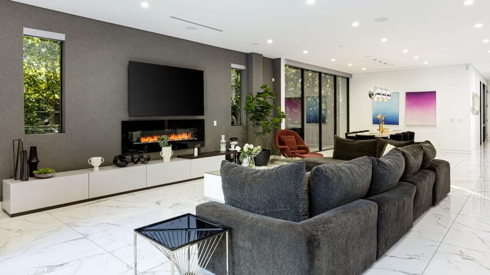 Sleek open-concept living room with_toggle fireplace, modern furnishings, and seamless indoor-outdoor flow.